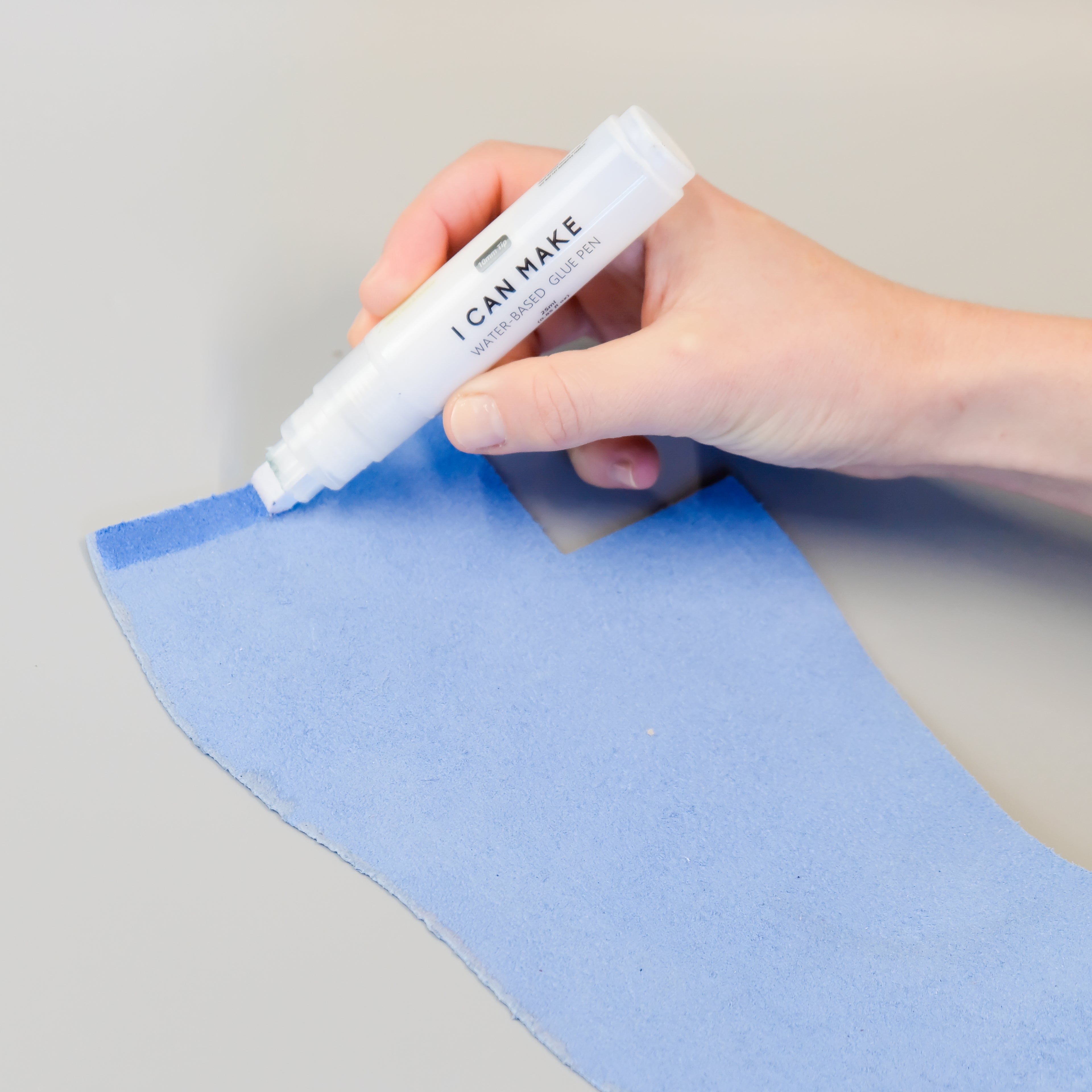 Hand applying glue with glue pen to leather